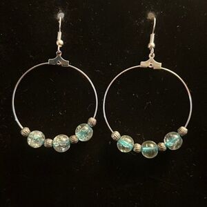 Handcrafted silver tone hoop earrings with clear and blue beading.